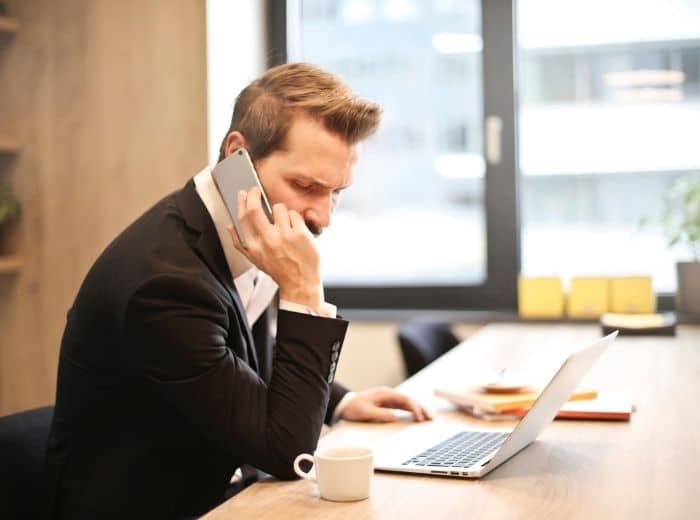 man belt achter laptop telefonische acquisitie