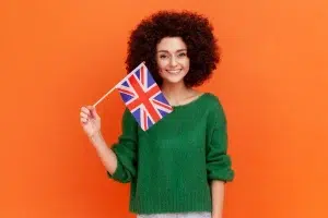 Smiling woman holding a UK flag, symbolizing international learning about the Collective Labour Agreement and Regulations in the Netherlands.