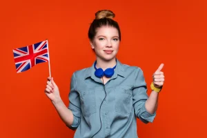 Introduction to the Collective Labour Agreement training in het Engels, jonge vrouw met Britse vlag en duim omhoog op een oranje achtergrond.