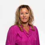 Team artra – vrouw in fuchsia blouse met halflang blond haar voor witte achtergrond