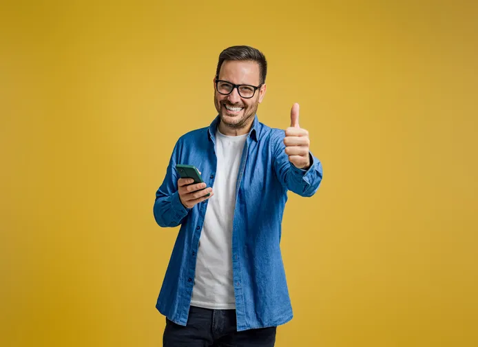 Lachende jonge man die zijn duim omhoog steekt als symbool dat hij enthousiast is over AI
