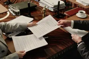 Wijzigingen uitzend-cao – twee personen wisselen officiële documenten uit in zakelijke setting