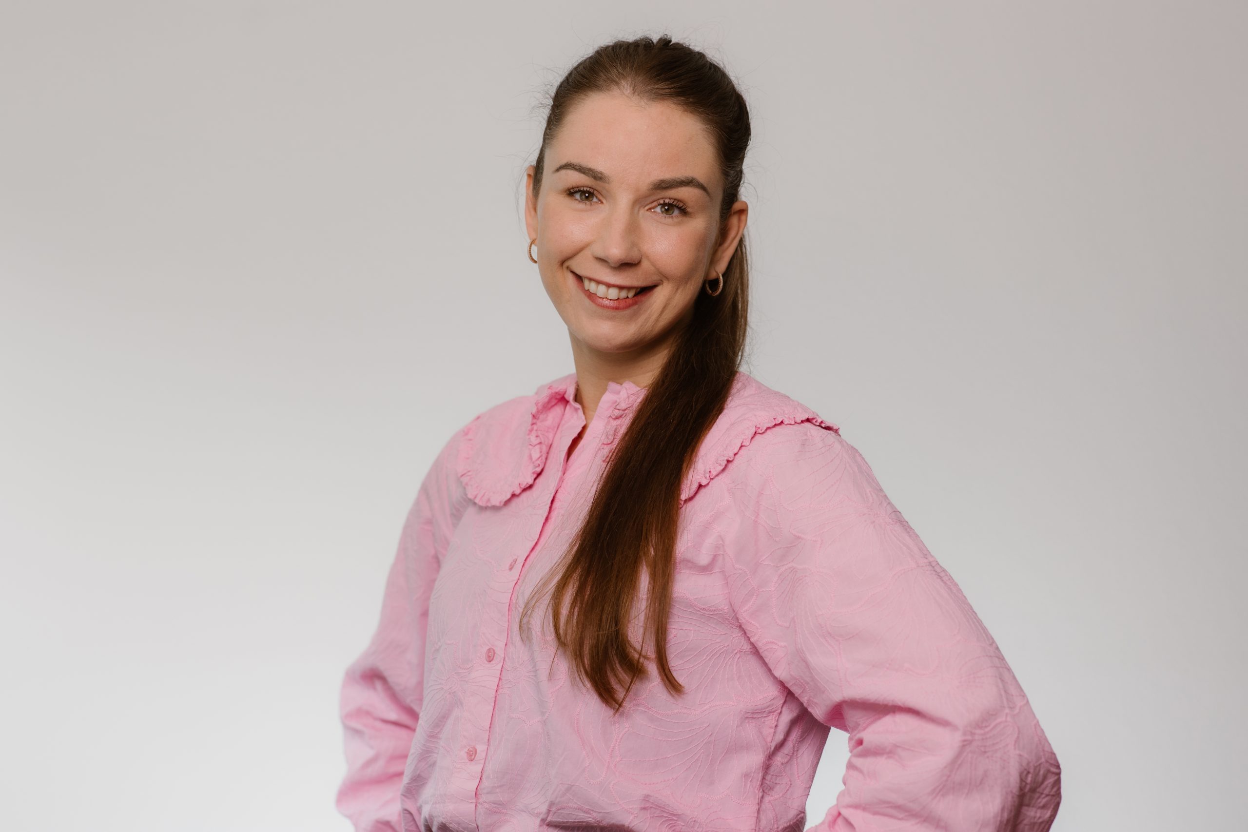 Team artra – vrouwelijke medewerker in roze blouse voor lichte achtergrond