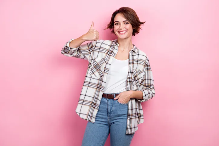 jonge lachende vrouw met haar duim omhoog als symbool voor een positieve leidinggevende
