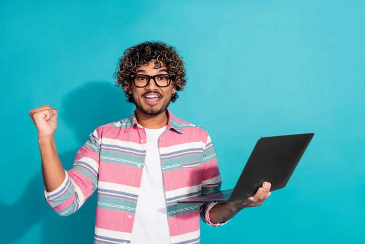 Lachende jonge man met laptop als symbool voor groeien als arbeidsmarktprofessional
