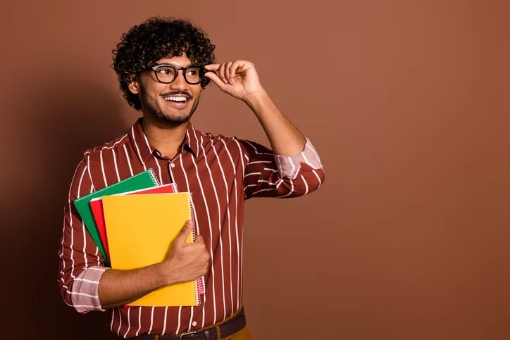 Lachende jonge man met gekleurde mappen in zijn hand als symbool voor een recruiter