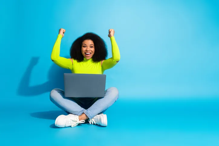 Juichende jonge vrouw met laptop als symbool voor zelfontwikkeling