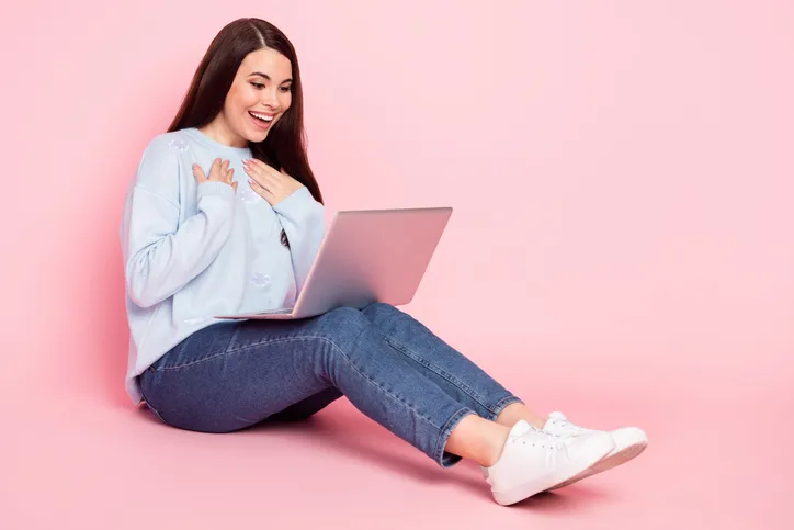Jonge vrouw die verrast naar haar laptop kijkt, als symbool van het belang van een goede onboarding van nieuwe medewerker