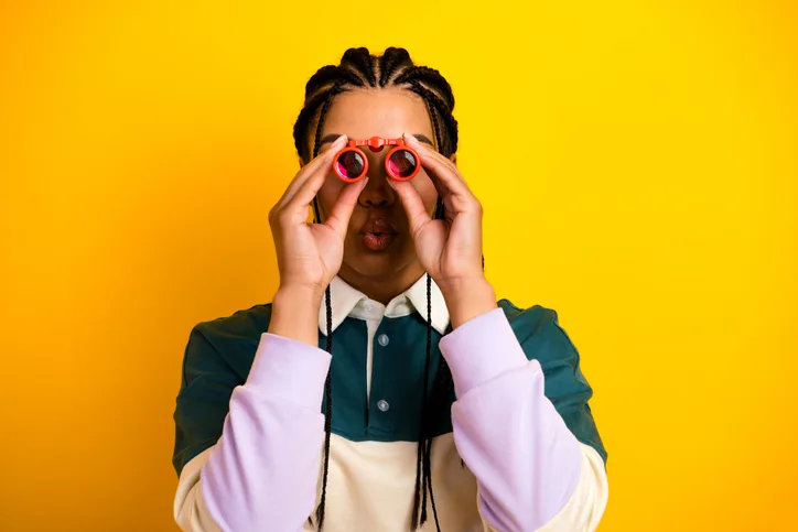 Jonge vrouw met verrekijker als symbool van het verdiepen in de candidate experience en employer brand 