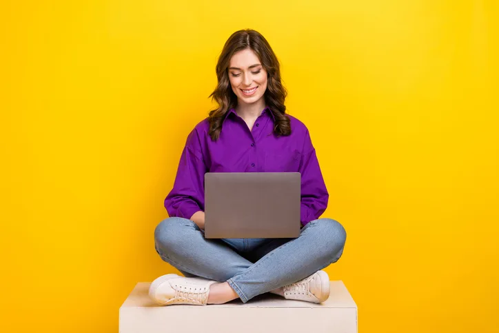 Jonge vrouw met een laptop op schoot als symbool voor searchen of sourcen