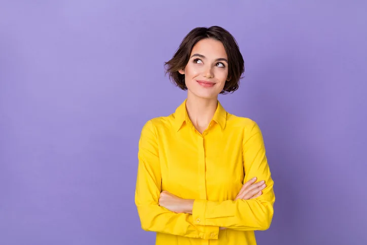 Jonge, glimlachende vrouw met haar armen over elkaar als symbool voor tevredenheid over loontransparantie