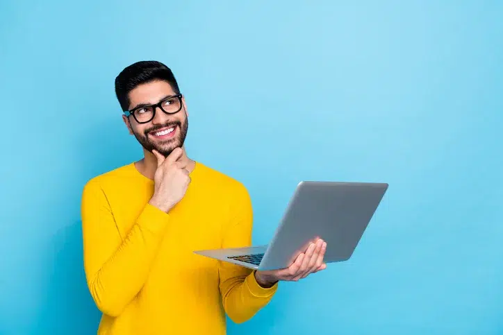 Jonge man met laptop in zijn hand als symbool voor een HR medewerker die zich afvraagt wat medewerkers écht nodig hebben in hun eerste 6 maanden
