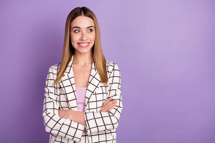 Jonge lachende vrouw in geruit pak als symbool voor aantrekkelijk werkgeverschap in detachering