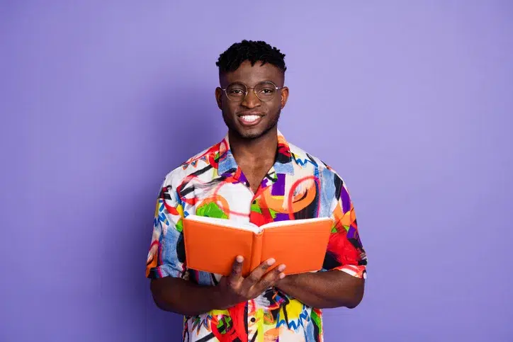Jonge lachende man met een boek in zijn handen als symbool van voorbereiding op de Wtta
