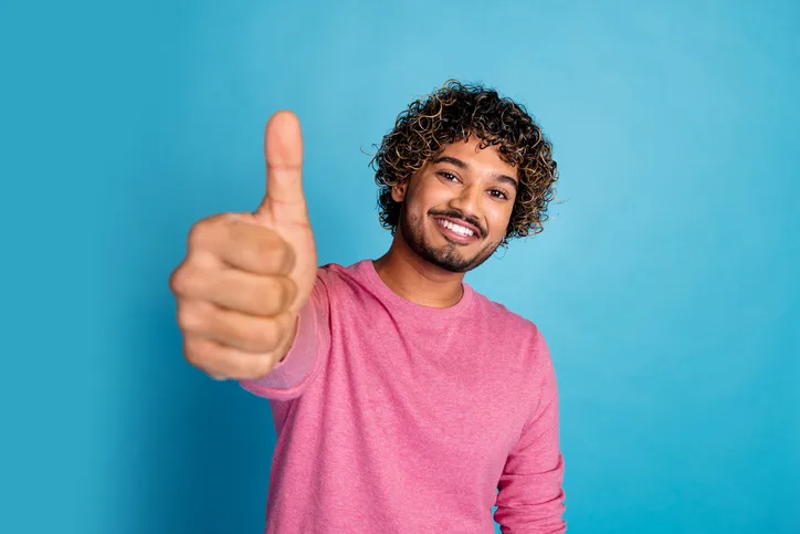 Jonge man met glimlach en opgestoken duim als symbool voor het herkennen van talent en potentieel bij het beoordelen van het cv
