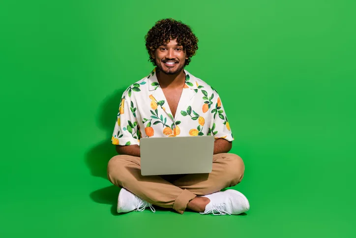 Jongen man met krullend haar en laptop op schoot als symbool voor detacheren met visie