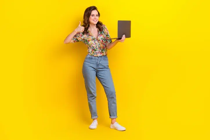 Jonge vrouw met laptop en opgestoken duim als symbool voor enthousiasme over de inzet van AI voor het creëren van beeldmateriaal