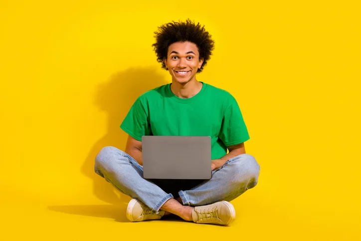 Jonge man met laptop op schoot als symbool flexibele detacheerders, ook in de zomerperiode