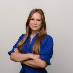 Vrouw in blauwe blouse met glimlach.