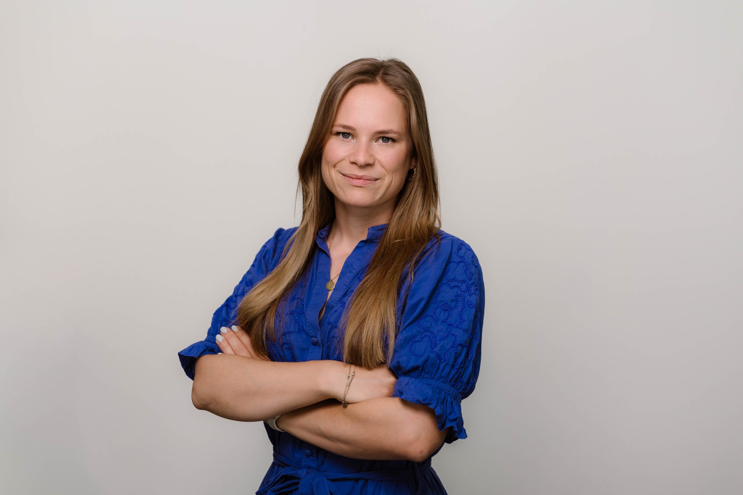 Vrouw in blauwe blouse met glimlach.