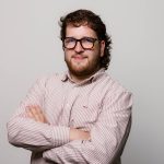 Jonge man met een bril en armen gekruist.